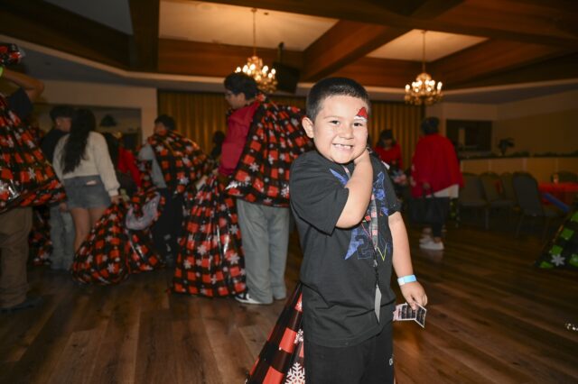 A young boy smiles at the camera after receiving a tote filled with gifts during the 21st Annual SBCSS CDS Holiday Celebration on December 18.