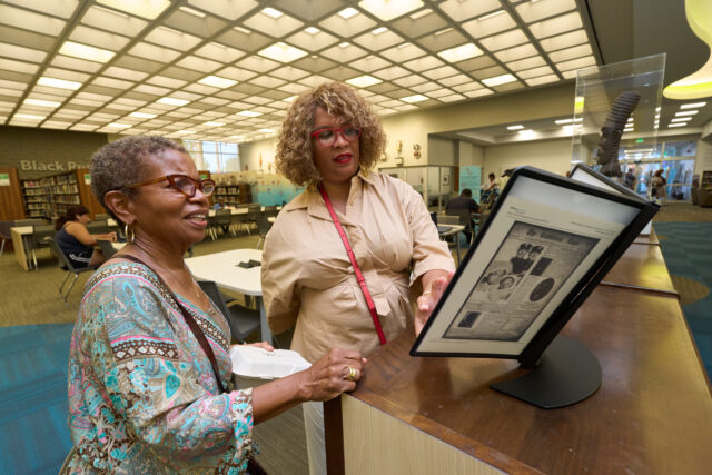 6dbc7693-71f8-4170-93f3-0fb1d16c9459 Exhibit curator Kellie Todd Griffin shares the Museum of Black Women and Girls Pop-Up with an oral history project participant at the A C Bilbrew Library.
